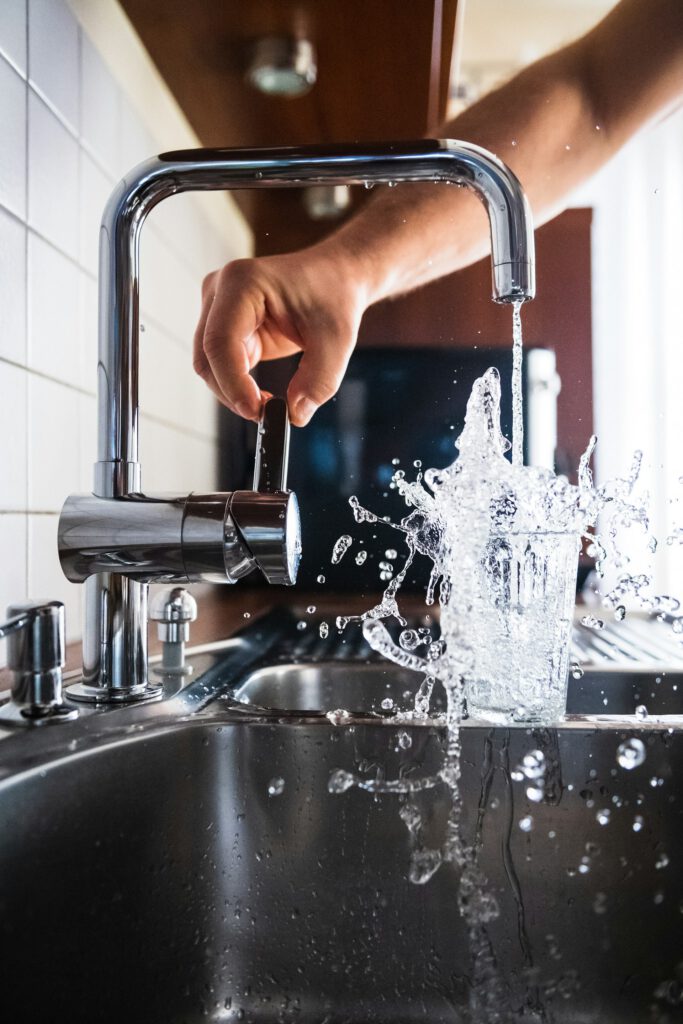 Plumber testing a running kitchen tap after an emergency repair