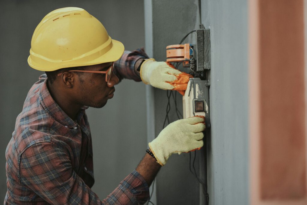 Gas Safe engineer in a hard hat testing a boiler control panel