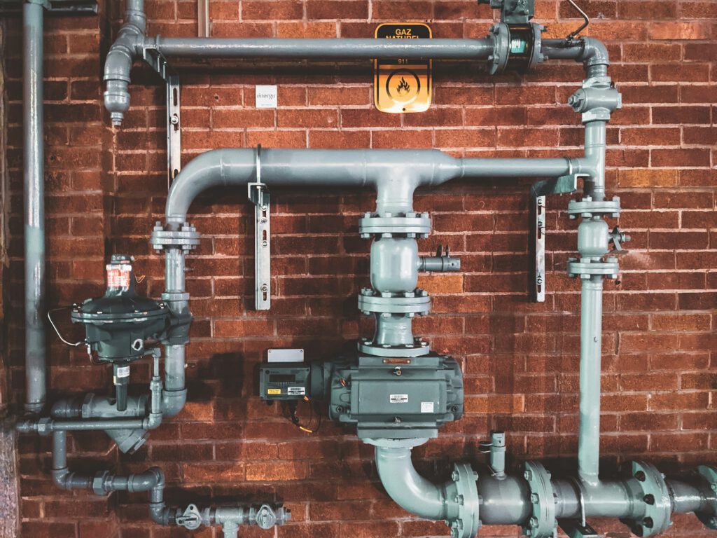 Drainage and water pipes with valves mounted on a red brick wall